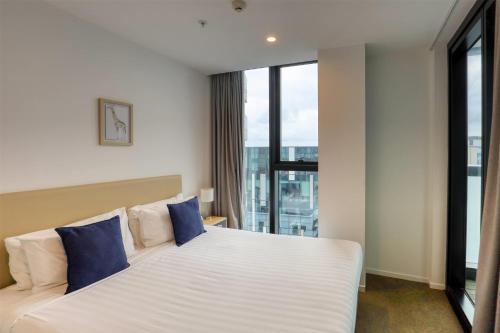 a bedroom with a large white bed with blue pillows at Ramada Suites by Wyndham Queenstown Remarkables Park in Queenstown