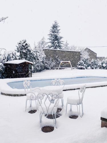 a swimming pool covered in snow with a table and chairs at Borda de Fadrín in Ipiés