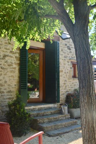 a house with a green door and stairs next to a tree at Borda de Fadrín in Ipiés
