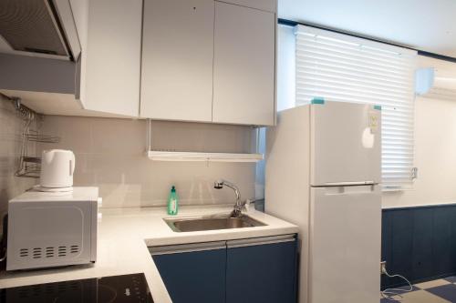 a kitchen with a white refrigerator and a sink at SloCruise in Gongju