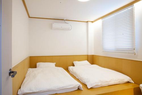 two beds in a room with a window at SloCruise in Gongju