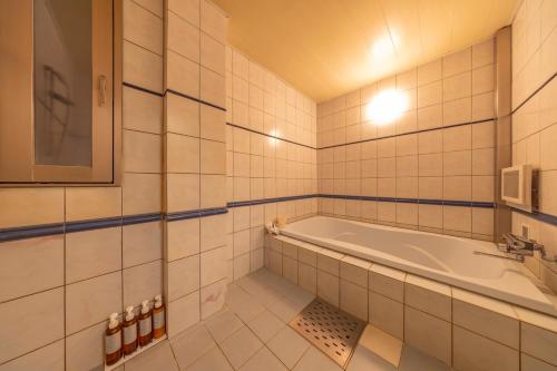 a white bathroom with a tub and a tv at HOTEL WiLL 大高 in Nagoya