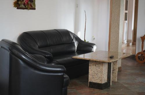 a black leather couch and a table in a room at Aquasalis in Câmpulung Moldovenesc