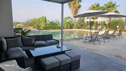 a couch and tables and umbrellas next to a pool at Villa Spilies in Peyia