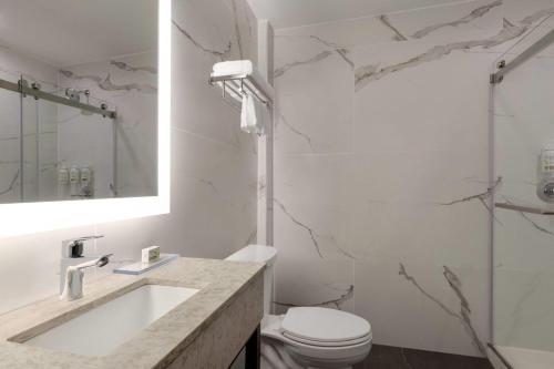 a bathroom with a sink and a toilet and a shower at Ramada by Wyndham Brooklyn Empire Blvd in Brooklyn