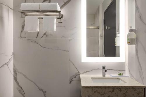 a white bathroom with a sink and a mirror at Ramada by Wyndham Brooklyn Empire Blvd in Brooklyn