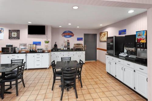 een keuken met witte kasten en zwarte tafels en stoelen bij Baymont by Wyndham Chester IL in Chester
