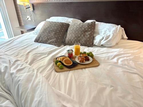 a tray of food and orange juice on a bed at Le Saint-Pierre in Mézidon-Canon