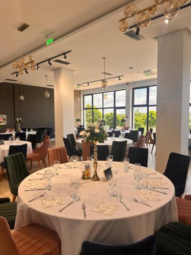 a dining room with white tables and chairs and windows at Vila Aleksandar in Orašac