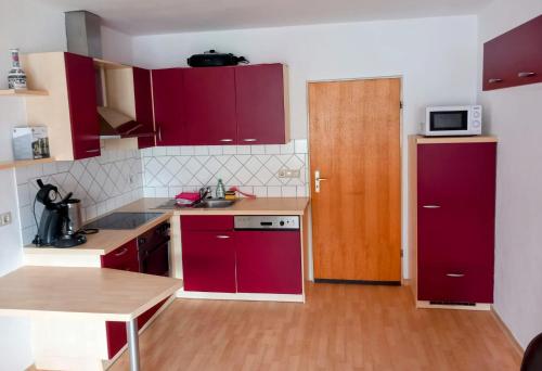 a kitchen with red cabinets and a red refrigerator at Pension Ochsen, Ferienwohnungen in Löffingen