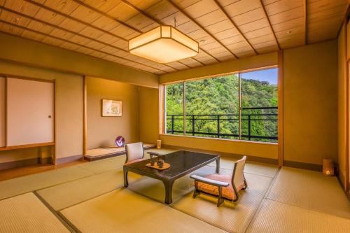 a room with a table and chairs and a large window at Ooedo Onsen Monogatari Premium Saiki Bekkan in Misasa