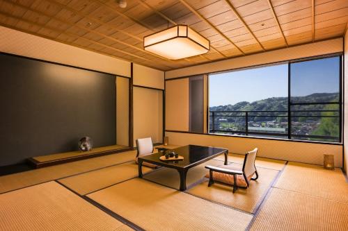 a dining room with a table and chairs and a large window at Ooedo Onsen Monogatari Premium Saiki Bekkan in Misasa