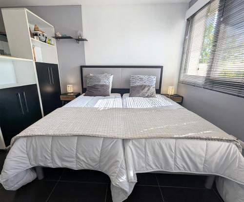 Un dormitorio con una cama grande con sábanas blancas. en Studio dans Villa avec Piscine, en Échenevex