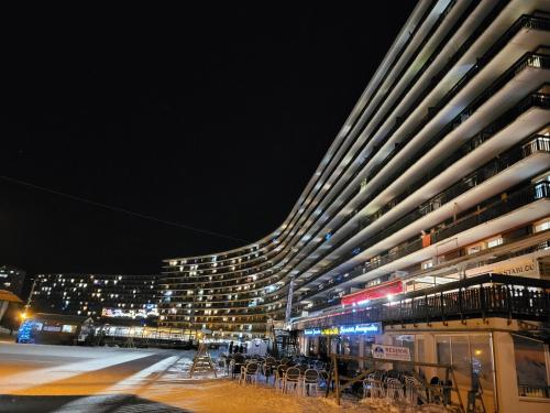 a large building with tables and chairs at night at VACANCES à SUPERDEVOLUY hautes Alpes 05250 in Superdevoluy