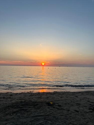 a sunset on the beach with the sun setting at Muli 1 Bedroom Apartment in (( Stan i Ri ))