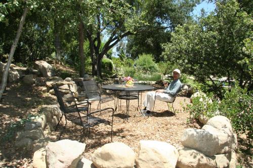 a man sitting at a table in a garden at Ojai Retreat & Inn in Ojai