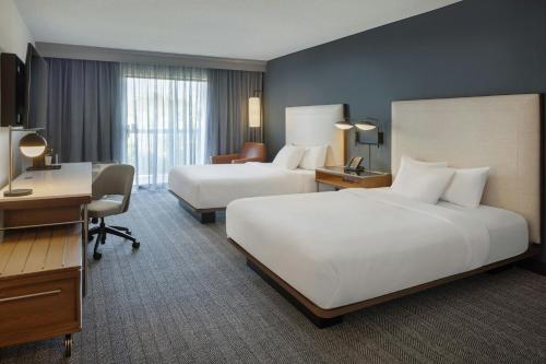a hotel room with two beds and a desk at Courtyard by Marriott Springfield Airport in Springfield