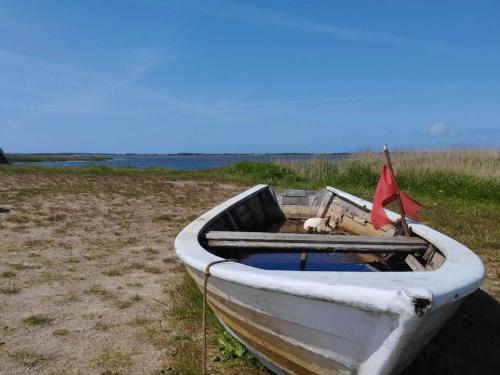 a white boat with a red flag in a field at 6 person holiday home in Ringkøbing in Ringkøbing
