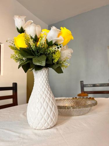 a white vase with yellow flowers on a table at Honeydream Villa & Studio Apartments in Diani Beach
