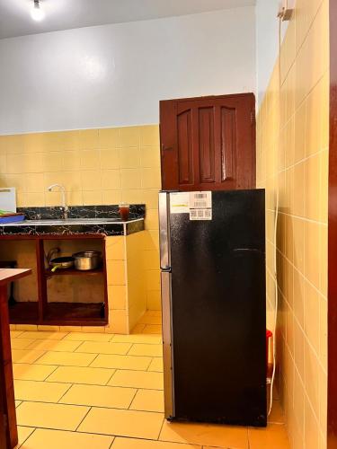a kitchen with a black refrigerator in a room at Honeydream Villa & Studio Apartments in Diani Beach
