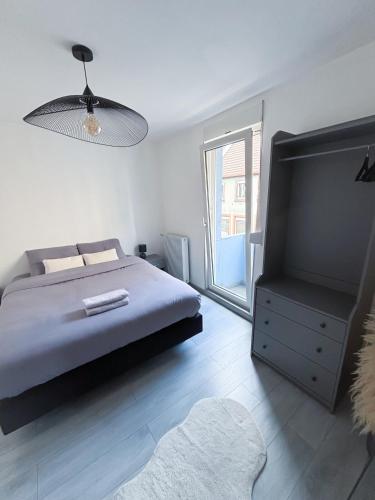 een slaapkamer met een bed en een groot raam bij Lescapade à Colmar in Colmar