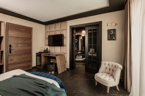 a bedroom with a bed and a chair and a television at Damare Resort & SPA in St Paul's Bay