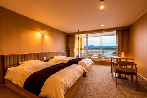 a bedroom with two beds and a table and a window at Ooedo Onsen Monogatari Premium Shirahama Gyoen in Shirahama