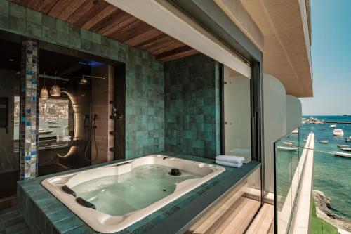 a bath tub with a view of the water at Damare Resort & SPA in St Paul's Bay