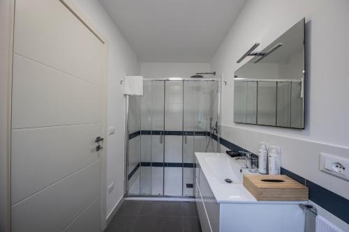 a white bathroom with a shower and a sink at Borgo a Mare in San Lucido