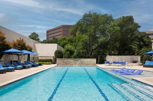 a swimming pool with blue chairs and umbrellas at Dallas-Addison Marriott Quorum by the Galleria in Addison