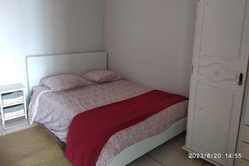 a small bedroom with a bed with a red blanket at Changement d'air près du volcan in Le Tampon