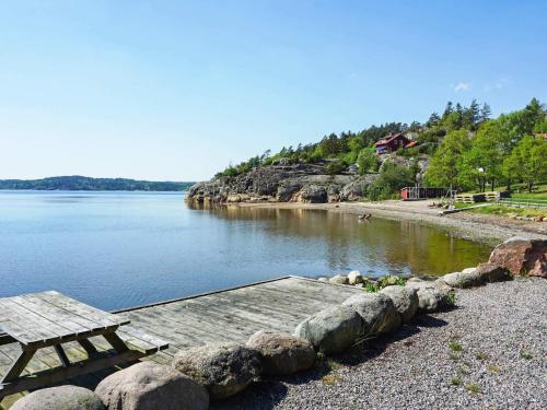 a picnic table and bench on the shore of a lake at 6 person holiday home in MUNKEDAL in Munkedal