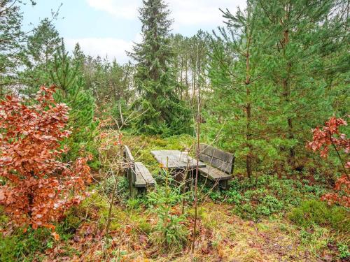 a picnic table and bench in the woods at 5 person holiday home in Herning-By Traum in Kølkær