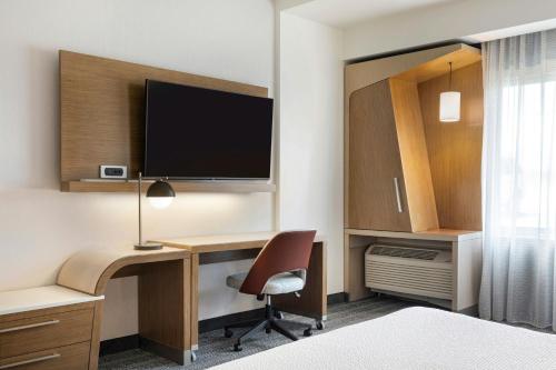 a hotel room with a desk with a computer and a tv at Courtyard by Marriott St. Louis St. Peters in Saint Peters
