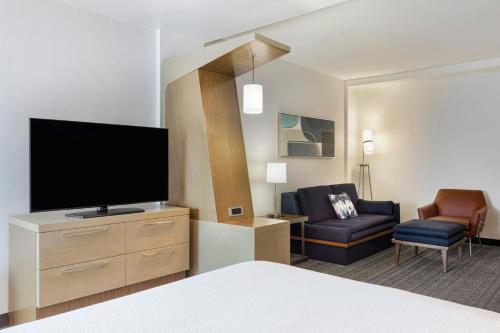 a hotel room with a bed and a tv and a chair at Courtyard by Marriott St. Louis St. Peters in Saint Peters