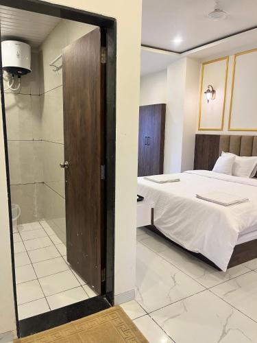 a bedroom with a bed and a glass door leading to a shower at Jeel Pearl Hotel in Udaipur