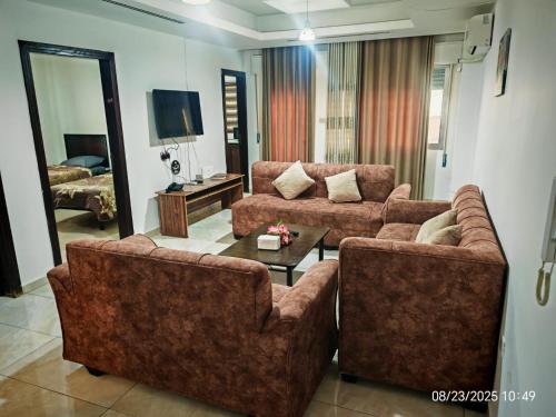 a living room with two couches and a tv at EVANNA SUITE AND HOTELs ايفانا للشقق الفندقيه و المفروشه in Amman