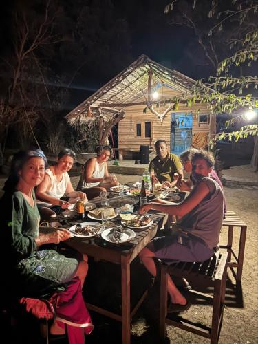 a group of people sitting around a table at night at Leopardbay Cabanas Arugambay in Arugam Bay