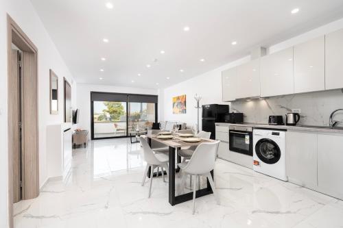 una cocina blanca con mesa y sillas. en Icon Luxury Apartments, en (( Kermetés ))