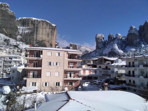 a building in the snow with mountains in the background at Διαμέρισμα Μαρία in Kalabaka