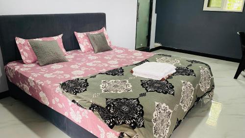 a bed with a pink and black blanket and pillows at Sagar Hotel 