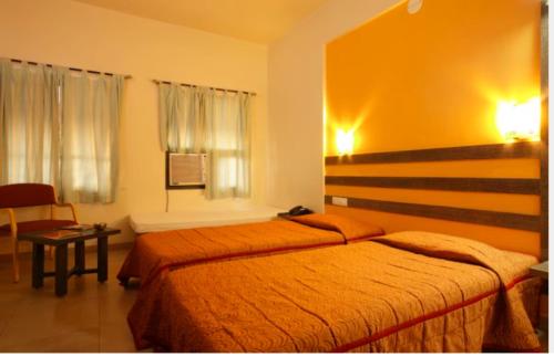 a hotel room with two beds and a chair at Hotel Orient Crown, Kolhapur in Kolhapur