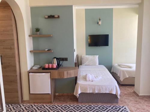 a bedroom with a bed and a desk and a tv at Olimpia Hotel in Fethiye