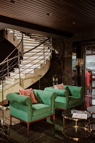 a living room with two green couches and a staircase at Damare Resort & SPA in St Paul's Bay