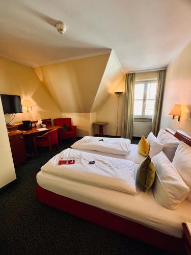 a hotel room with two beds and a desk at Hotel Weisses Lamm in Veitshöchheim