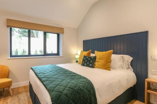 a bedroom with a large bed with yellow pillows at The Hideaway at Hoddington Arms in Upton Grey