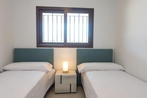 two beds in a room with a window at Modern 2BR Apt with own Terrace & Pool access in Pulpí
