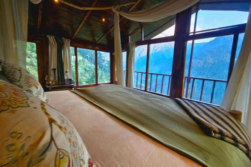a bedroom with a bed and a large window at Parvati's Lap Mountain Villa- MEGHBARI in Kasol