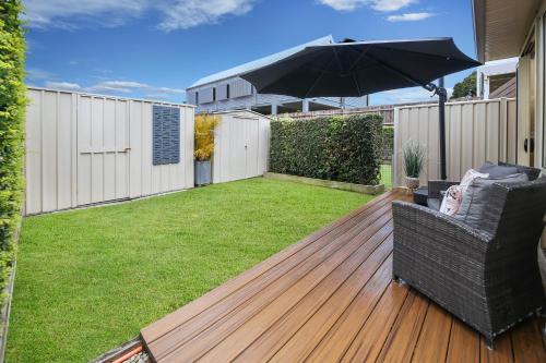 a patio with an umbrella and a chair on a deck at Pet Pawfect Coastal Stay in Maroochydore