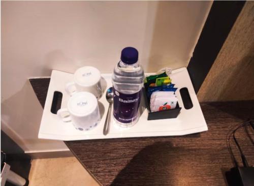 a tray with a bottle of water and cups on a table at Hotel Orient Crown, Kolhapur in Kolhapur